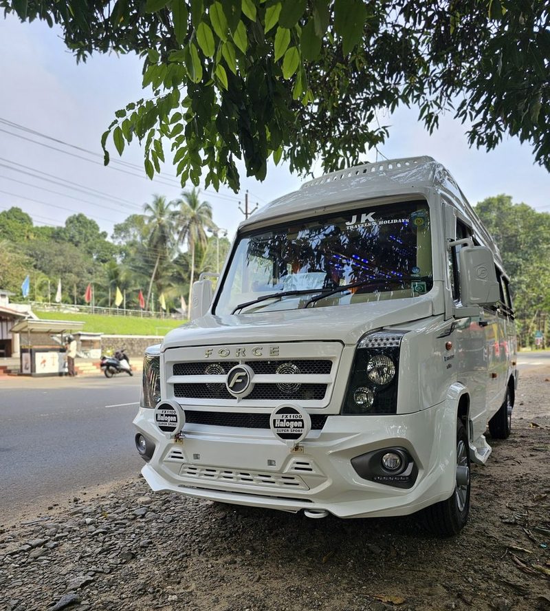 The JK Travels tempo traveller parked on a tree-lined Kerala road